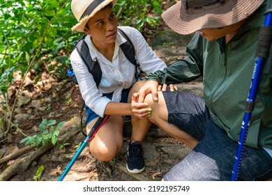 Asian Family Couple On Summer Holiday Vacation. Mature Adult Couple Hiking Together In Forest. Senior Man Injured On Knee During Trekking With His Wife. Adventure Travel And Health Care Concept.