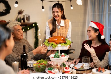 Asian family cousin woman smile while serving roasted turkey meal in white dish on the table with enjoyment for winter festival celebration in Merry Christmas dinner at the hosting home - Powered by Shutterstock