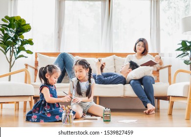 Asian Family With Cute Daughters Painting Art In Living Room At Home