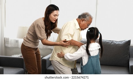 Asian Family, Daughter And Granddaughter Take Care Support Senior Mature Grandfather Who Is Suffering From Knee Pain Walking Outside To Take A Walk And Grandpa With A Stick, Elderly Health Care