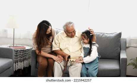 Asian Family, Daughter And Granddaughter Take Care Support Senior Mature Grandfather Who Is Suffering From Knee Pain Walking Outside To Take A Walk And Grandpa With A Stick, Elderly Health Care