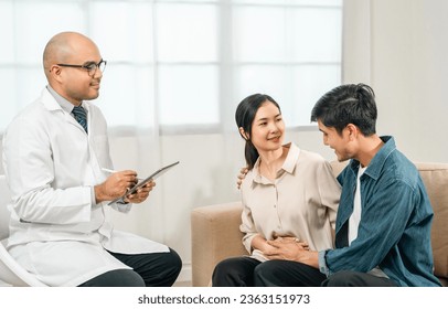 Asian family discussing fertility with a pediatrician. Young couple patients in fertility clinic consulting about IVF or IUI with doctor. Couple relationship therapy with a counselor - Powered by Shutterstock