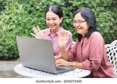 Asian Family Doing Bye Bye Pose And Making A Video Call To Friends At Home. Senior Mature And Young Woman Say Hi To Their Family While Using Laptop In Home Garden.