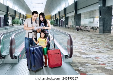 Asian Family Doing Holiday Trip And Looking A Map On The Digital Tablet At The Airport Hall