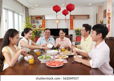 Asian family eating at big table for New Year celebration; couplets with best wishes for coming year in the background