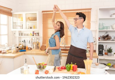 Asian Family Enjoy Cooking Salad And Dancing Together In Kitchen Room At Home.