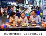 Asian family enjoy eating food on street food restaurant with crowd of people at Yaowarat road, Bangkok