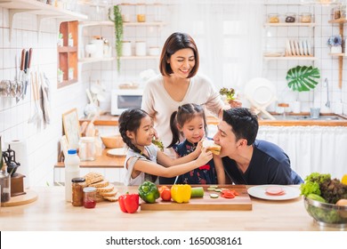 Asian family enjoy playing and cooking food in kitchen at home - Powered by Shutterstock