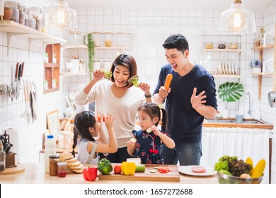 Asian Family Enjoy Playing And Cooking Food In Kitchen At Home