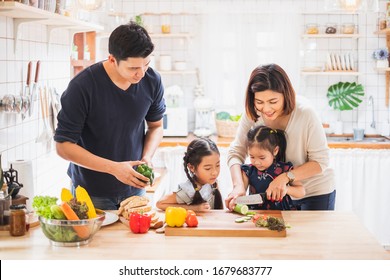 Asian Family Enjoy Playing And Cooking Food In Kitchen At Home