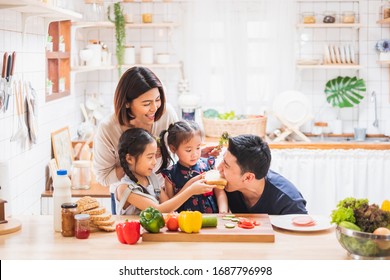 Asian Family Enjoy Playing And Cooking Food In Kitchen At Home