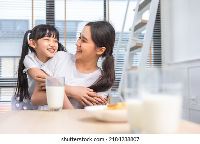 Asian  Family Enjoying Breakfast At Living Room. Little Girl Daughter Sitting On Table, Drinking Milk With Smiling Father And Mother In Morning. Happy Family At Home.