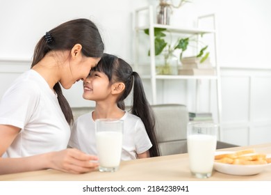 Asian  Family Enjoying Breakfast At Living Room. Little Girl Daughter Sitting On Table, Drinking Milk With Smiling Father And Mother In Morning. Happy Family At Home.