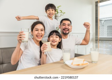 Asian  family enjoying breakfast at living room. little girl daughter sitting on table, drinking milk with smiling father and mother in morning. Happy family at home. - Powered by Shutterstock