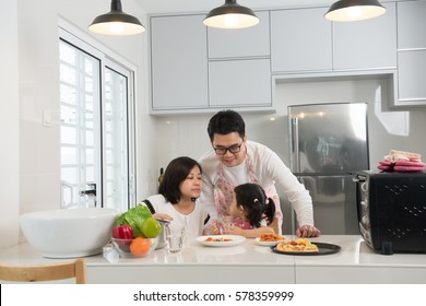 Asian Family Enjoying And Cooking Pizza