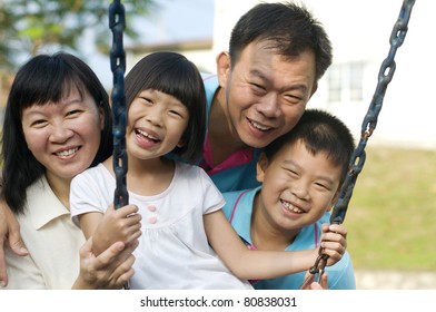 Asian Family Enjoying Morning Sunshine And Having Fun At The Playground