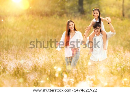 Asian family father, mother and daughter play togather in the outdoor park with sunrise and goldent colour, this image can use for family, relax, freedon, summer and travel concept