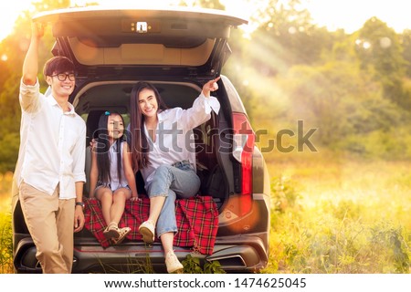 Asian family father, mother and daughter play togather in the Car in outdoor park with sunrise and goldent colour, this image can use for family, relax, freedon, summer and travel concept