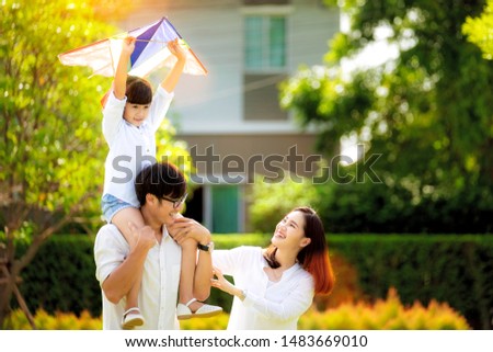 Asian family father, mother and daughter play a kite in the outdoor park in village near thay home, this image can use for family, relax, freedon, summer and travel concept