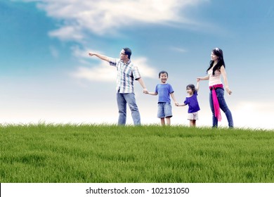 Asian Family Of Father, Mother, And Two Kids  Having A Quality Time In Meadow. Shot At Summer