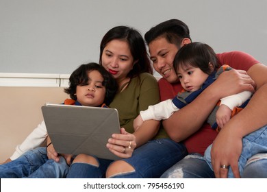 Asian family gathered together to watch a movie on tablet computer