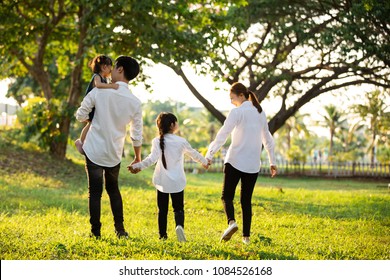 Asian Family Are Going Out Of The House , Parents And Children Were Walking Hand In Hand Together A Happy In Garden.
