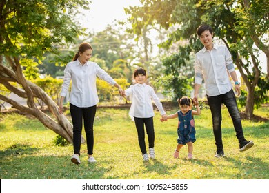 Asian Family Are Going Out Of The House , Parents And Children Were Walking Hand In Hand Together A Happy In Garden.