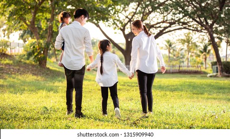 Asian Family Are Going Out Of The House , Parents And Children Were Walking Hand In Hand Together A Happy In Garden.
