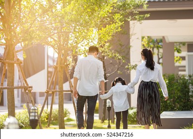 Asian Family Are Going Out Of The House , Parents And Children Were Walking Hand In Hand Together A Happy In Garden.