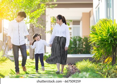 Asian Family Are Going Out Of The House , Parents And Children Were Walking Hand In Hand Together A Happy In Garden.