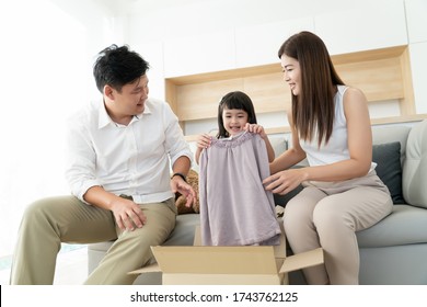 Asian Family Happiness Unpacking Open Parcel Box On Sofa Or Couch Get New Clothing Surprise For Kids, Parent Order T-shirt Fitting Trying Size For Children From Shopping Online Shop Application 