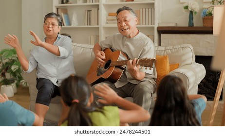 asian family Happy Multi Generation Family is Spending wonderful time at home Grandfather is Playing an Acoustic Guitar while Other Family Members are Singing and Enjoying in Together happy lifestyle - Powered by Shutterstock