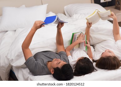 Asian Family Happy Reading And Play Together On The Bed Before Sleep. Soft Focusing On Children Center.