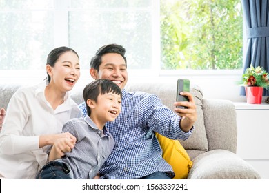 Asian Family Happy And Use Smartphone Taking A Selfie Photo Together In The Living Room.