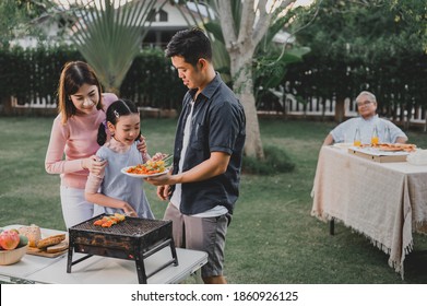 Asian Family Having A Barbecue Party At Home. Cooking Grilled Bbq For Dinner In Backyard. Togetherness And Lifestyle On Summer Holiday.