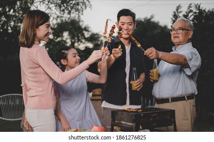 Asian family having a barbecue party at home. Cooking grilled bbq for dinner in backyard. Lifestyle and togetherness on summer holiday. - Powered by Shutterstock