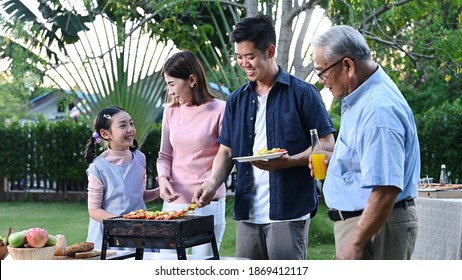 Asian Family Having A Barbecue Party At Home. Cooking Grilled Bbq For Dinner In Backyard. Lifestyle On Summer Holiday.