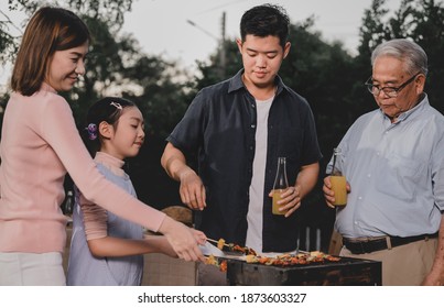 Asian Family Having A Barbecue Party At Home. Cooking Grilled Bbq For Dinner In Backyard. Lifestyle On Summer Holiday.