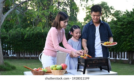 Asian Family Having A Barbecue Party At Home. Cooking Grilled Bbq For Dinner In Backyard. Lifestyle On Summer Holiday.