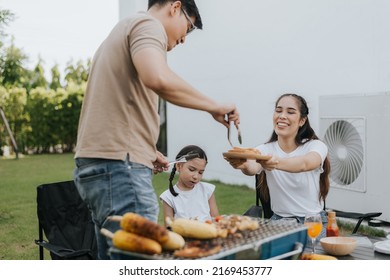 Asian Family Having Dinner In The Backyard At Home. Happy Family With Little Child Camping And Have Fun In House Backyard Outside. Barbecue Time, Family Activities Conccept.