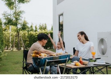 Asian Family Having Dinner In The Backyard At Home. Happy Family With Little Child Camping And Have Fun In House Backyard Outside. Barbecue Time, Family Activities Conccept.