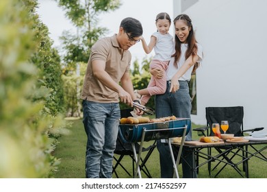 Asian family having dinner in the backyard at home. Happy family with little child camping and have fun in house backyard outside. Barbecue time, Family activities conccept. - Powered by Shutterstock