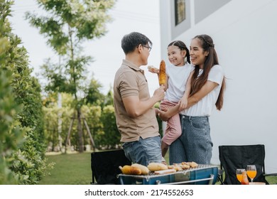 Asian Family Having Dinner In The Backyard At Home. Happy Family With Little Child Camping And Have Fun In House Backyard Outside. Barbecue Time, Family Activities Conccept.