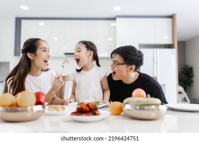 Asian family having meals together and showing thumbs up at home happily, Happy young parents are having fun with their little daughter during lunch at the dining table. - Powered by Shutterstock