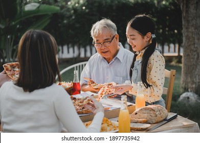 Asian Family Having Pizza In Garden At Home. Parent With Kid And Grandfather Lifestyle In Backyard.