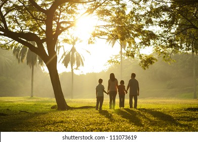 Asian Family Holding Hands And Walking Towards Light