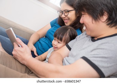 Asian Family Holding A Tablet Computer And Looking At It