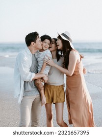 Asian Family Hugging and Walking Along the Beach with Father, Mother, Teenage Girl, Boy, during Sunset on the Shore with Ocean Background and Sunlight