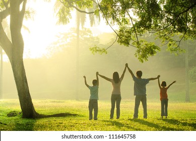 An Asian Family Jumping In Joy In The Park During A Beautiful Sunrise, Backlight