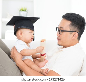 Asian family lifestyle at home. Baby with graduation cap holding certificate. Child and father early education concept.